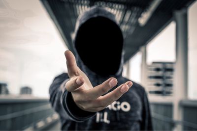 Man with obscured face gesturing in footbridge