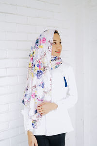 Woman holding umbrella standing against white wall