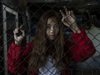 Portrait of a young woman looking through fence