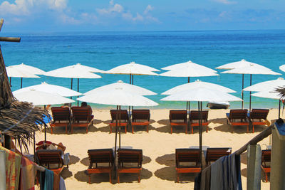 Row of blur white umbrellas with sun loungers on the beach against the blue ocean