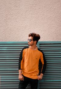 Portrait of young man standing against wall