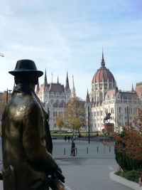 Statue in city against sky
