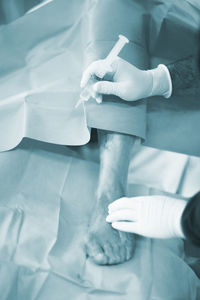 High angle view of doctor injecting syringe in patient foot