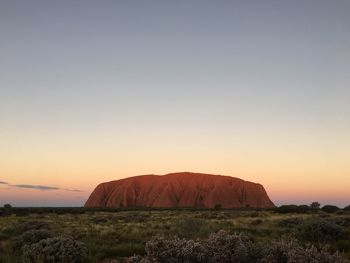 Scenic view of rocks on field against sky during sunset