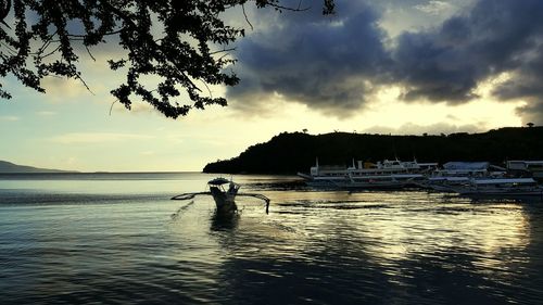 Boats in sea against cloudy sky