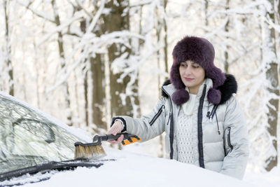 Woman removing snow on car