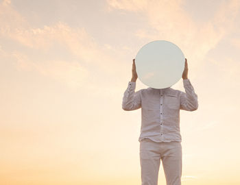 Rear view of woman standing against sky during sunset