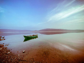 Boat moored on beach against sky