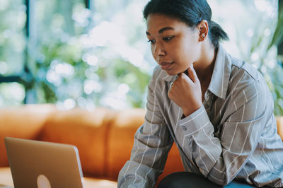 Young woman using laptop while sitting on chair