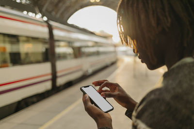 Young man using smart phone while waiting at railroad station