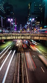 High angle view of light trails on city street by buildings