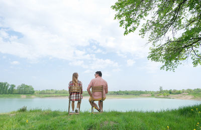 Rear view of couple walking on beach against sky