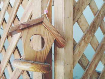 Low angle view of birdhouse hanging on roof against wall