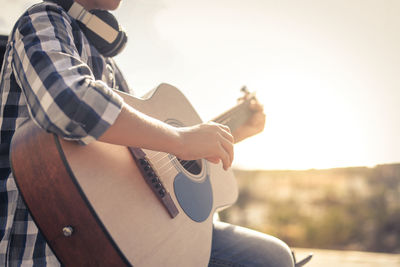 Midsection of boy playing guitar