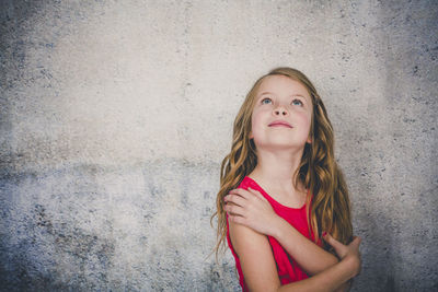 Portrait of a smiling girl standing against wall