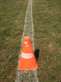 Bright orange white plastic cone on painted white line. very dry football green playground