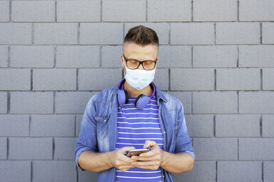 Man using mobile phone against brick wall