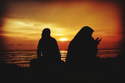 Silhouette people against sea during sunset