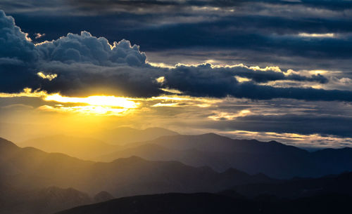 Scenic view of mountains against cloudy sky at sunset