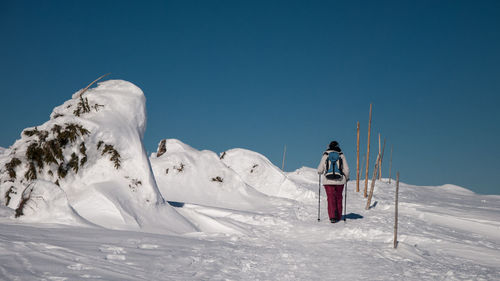 Man skiing on snowcapped mountain against clear sky