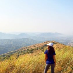 Rear view of woman standing on mountain against sky