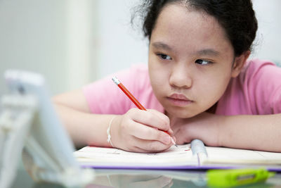 Asia young girl learning online at home with wring book