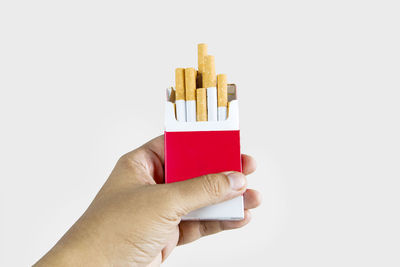 Close-up of hand holding pencils against white background