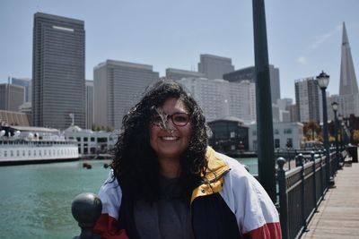 Woman standing on pier seven by transamerica pyramid and buildings in city