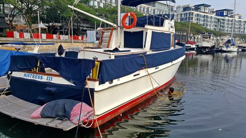 Boats moored in river with city in background