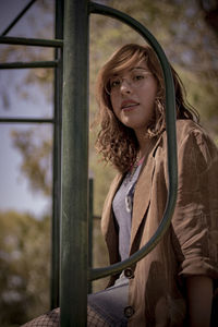 Portrait of young woman sitting by pole