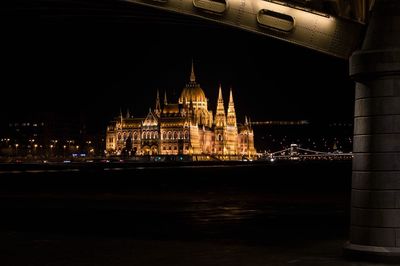 Illuminated hungarian parliament building by danube river at night