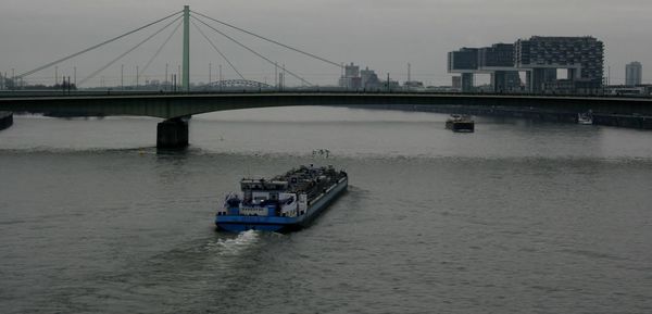 Boat sailing on river in city against sky