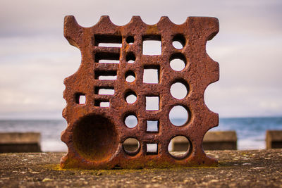 Close-up of rusty metal on beach against sky