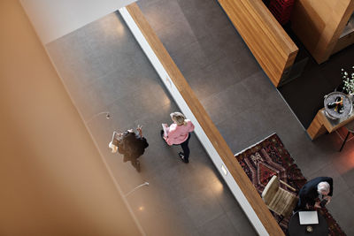 High angle view of female colleagues discussing while walking in corridor at office