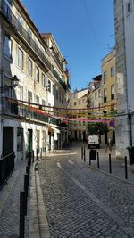 Street amidst buildings against clear blue sky