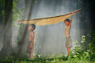 Happy friends standing by tree in forest