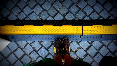 Low section of person standing on yellow line