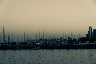 Sailboats moored at harbor against sky during sunset
