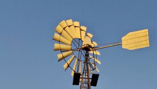 Low angle view of windmill against clear blue sky