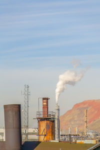 Smoke emitting from factory against sky