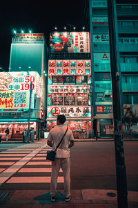 Rear view of man walking on street at night