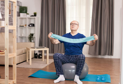 Full length of senior man exercising at home