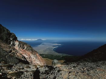 Scenic view of sea and mountains against blue sky