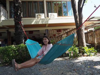 Portrait of woman sitting on hammock against plants