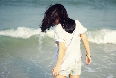 Rear view of young woman standing in sea