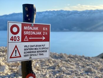 Close-up of road sign by sea against sky