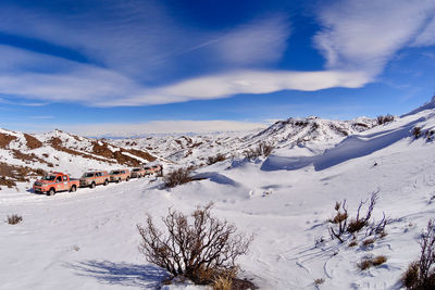 Scenic view of snowcapped mountains against cloudy blue sky on sunny day