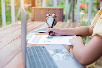 Close-up of woman holding paper with text on table