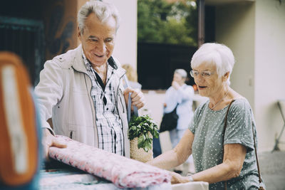 Senior couple shopping for textile at street market in city