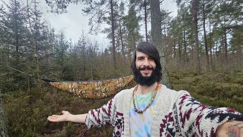 Portrait of smiling woman standing against trees